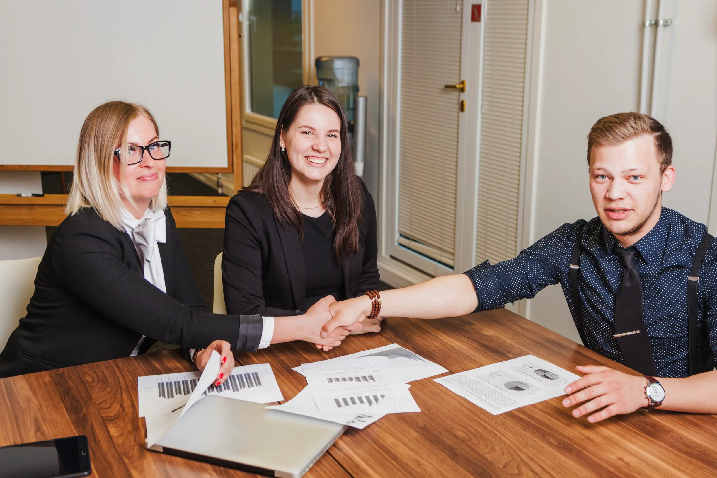 people-sitting-desk-smiling-shaking-hands